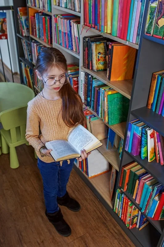 Dziecko wybiera książkę w bibliotece szkolnej