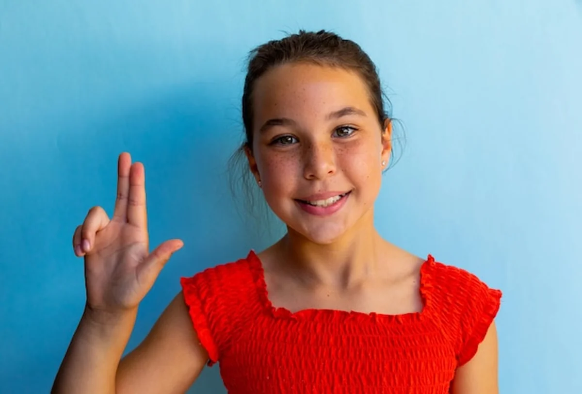 Uczennica migająca literę „W” na niebieskim tle