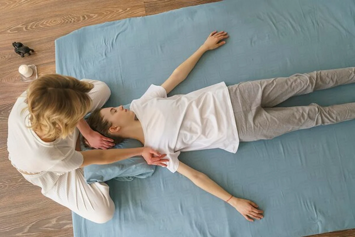 Masażystka wykonuje tajski masaż szyi i ramion na podłodze