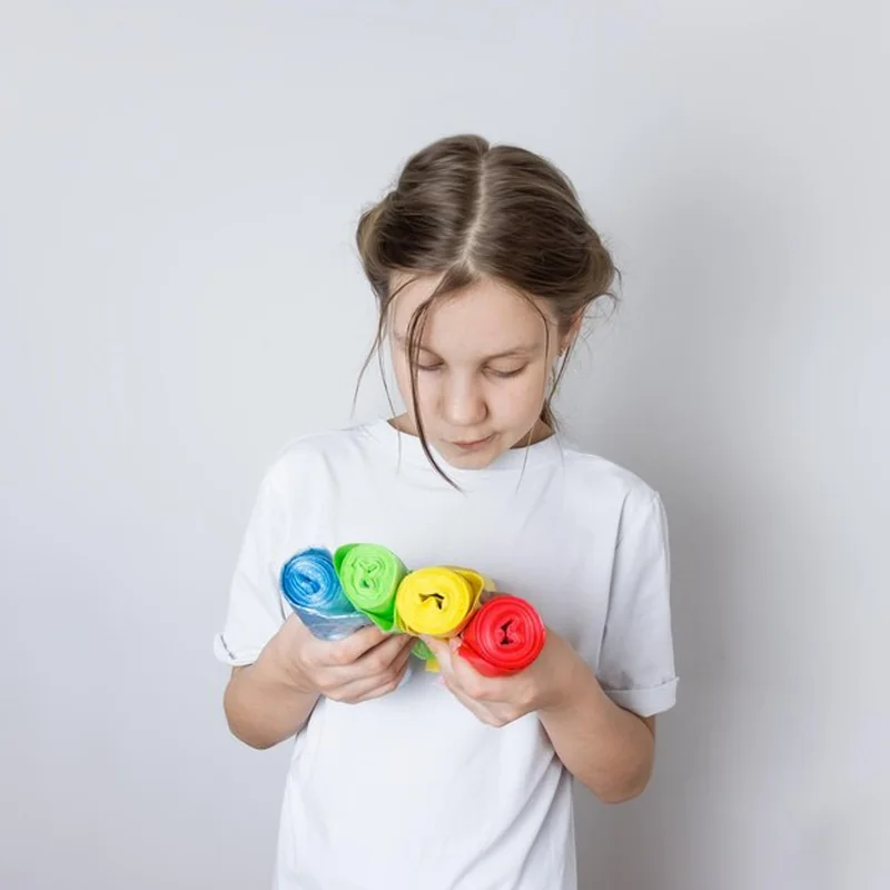 Dziecko trzymające kolorowe worki na śmieci do recyklingu