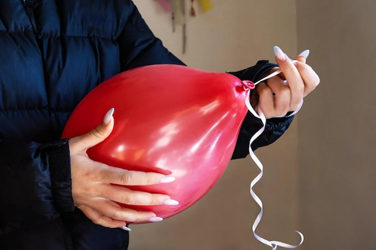 Kobieta wiążąca wstążkę na czerwonym balonie