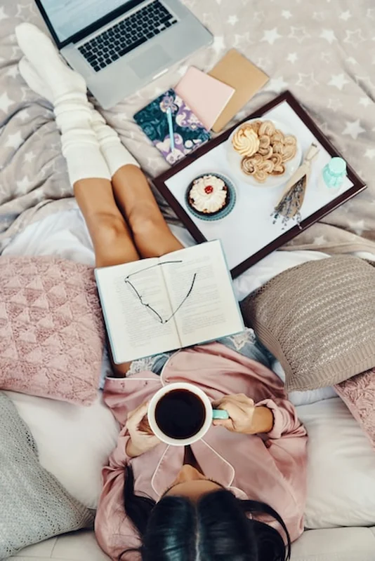 Młoda kobieta w piżamie pije kawę w łóżku