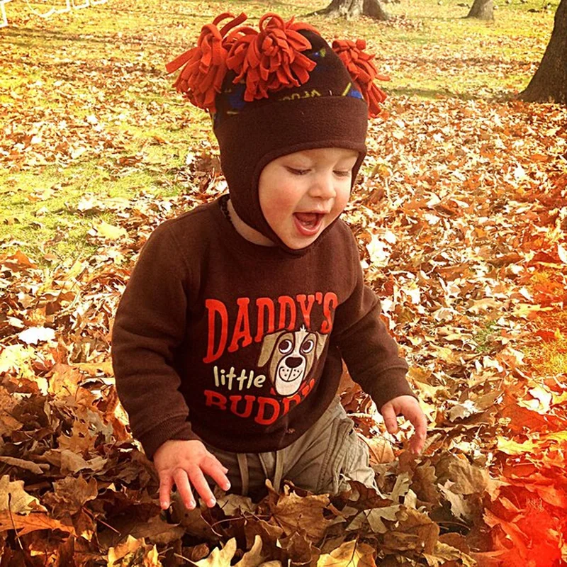 Mały chłopiec bawiący się upadłymi liśćmi jesienią w przedszkolu
