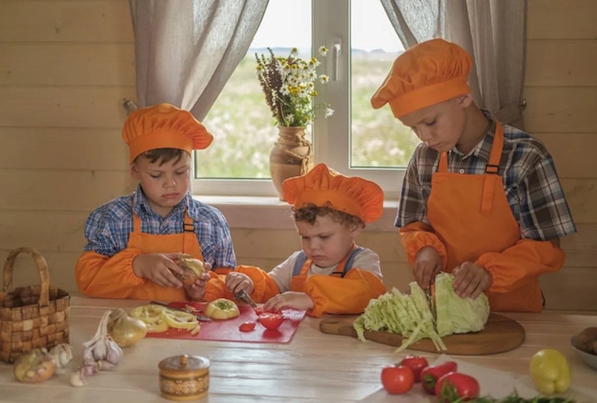 Trzech młodych szefów kuchni kroi warzywa na stole