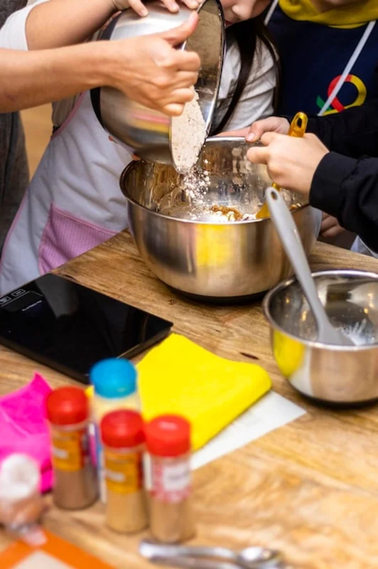 Cukiernik dodaje mąkę, pomaga dziewczyna podczas warsztatów ciasteczkowych