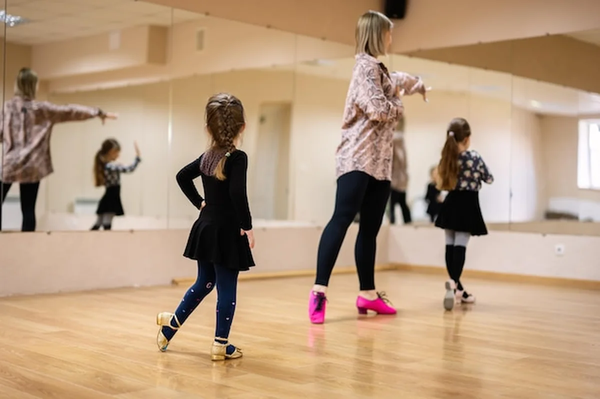 Młode dziewczyny tańczą z instruktorem w studiu tańca