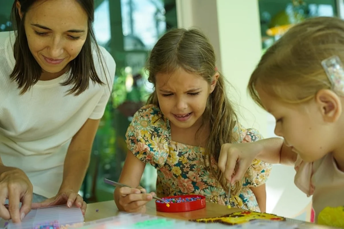 Nauczycielka uczy dwie dziewczyny montować termo mozaikę