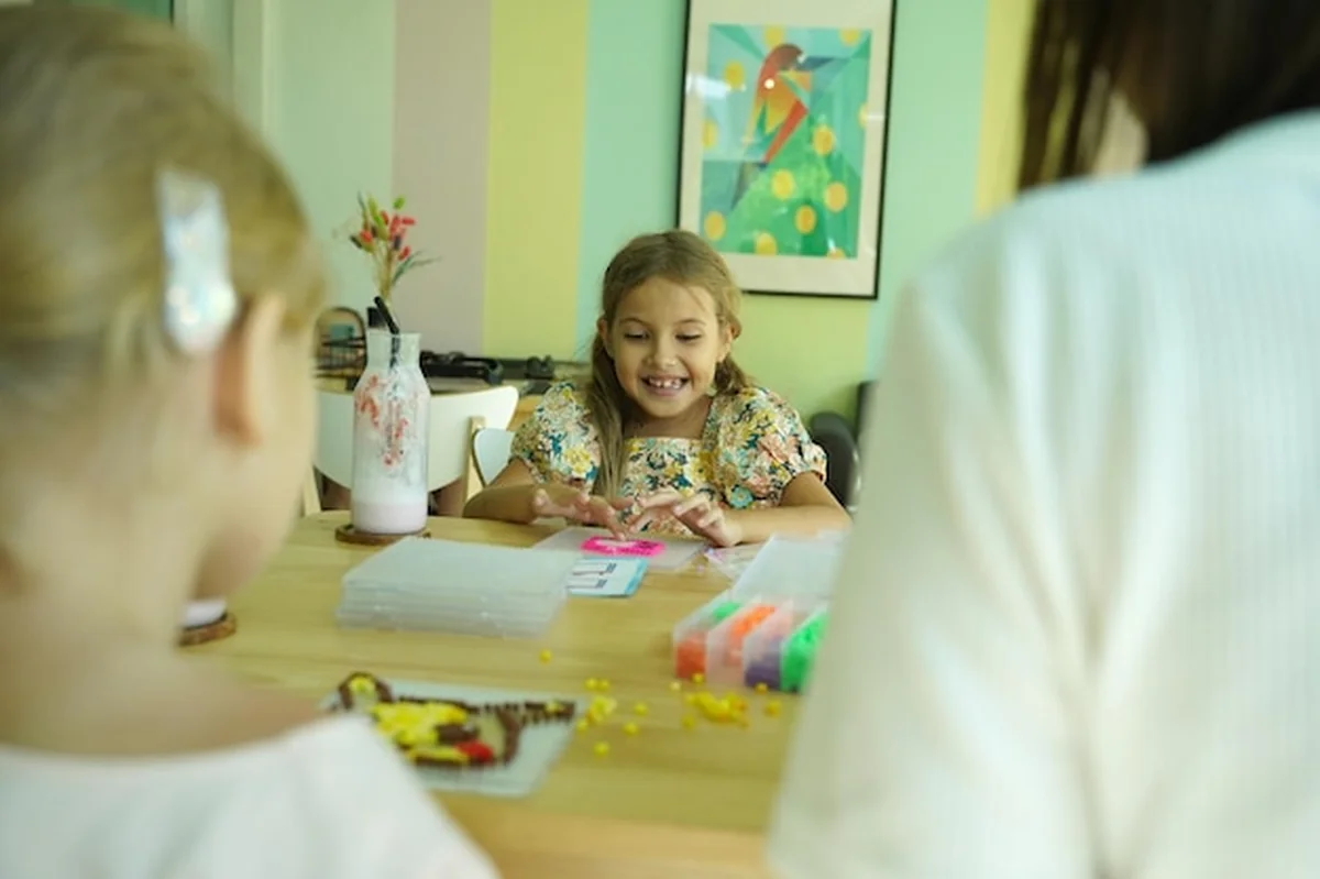 Nauczycielka uczy dwie dziewczyny montażu termo mozaiki w warsztacie