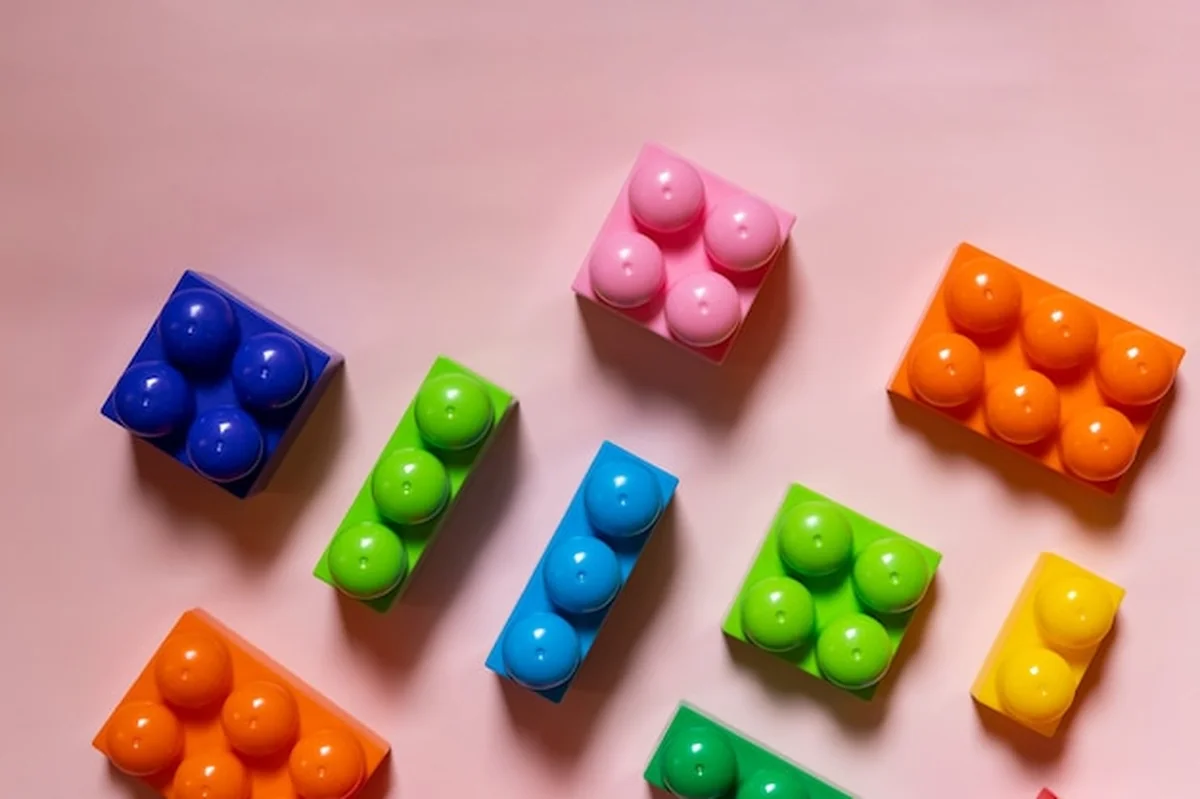 Kolorowe plastikowe klocki konstrukcyjne na różowym tle