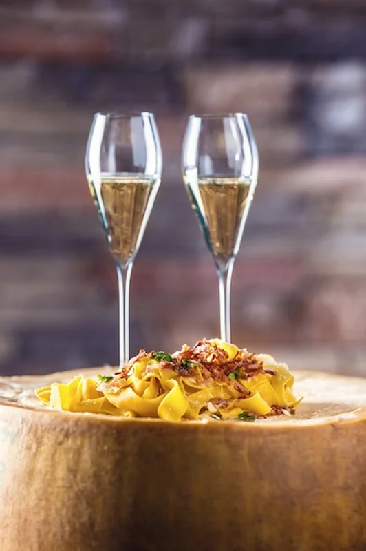 Włoski makaron pappardelle z aperitifem na dużym bloku sera parmezan