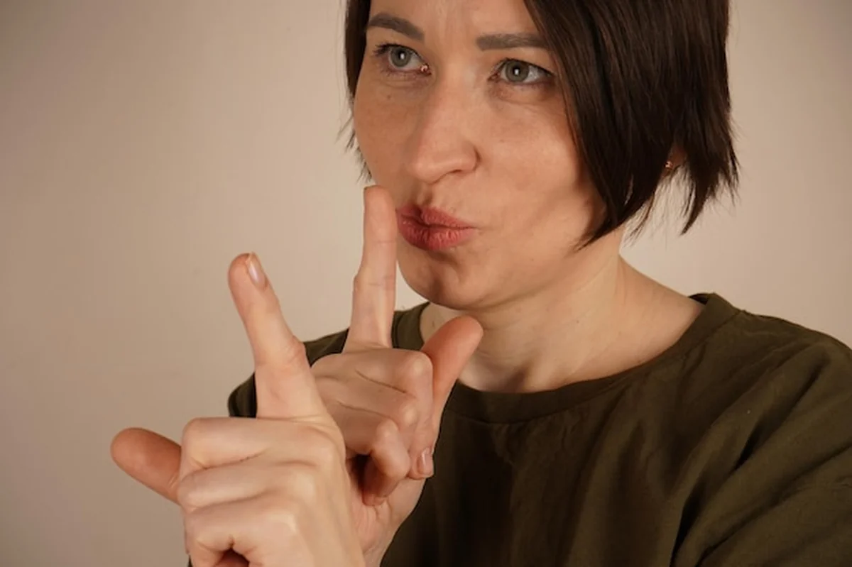 Dojrzała kobieta trzyma palec na ustach