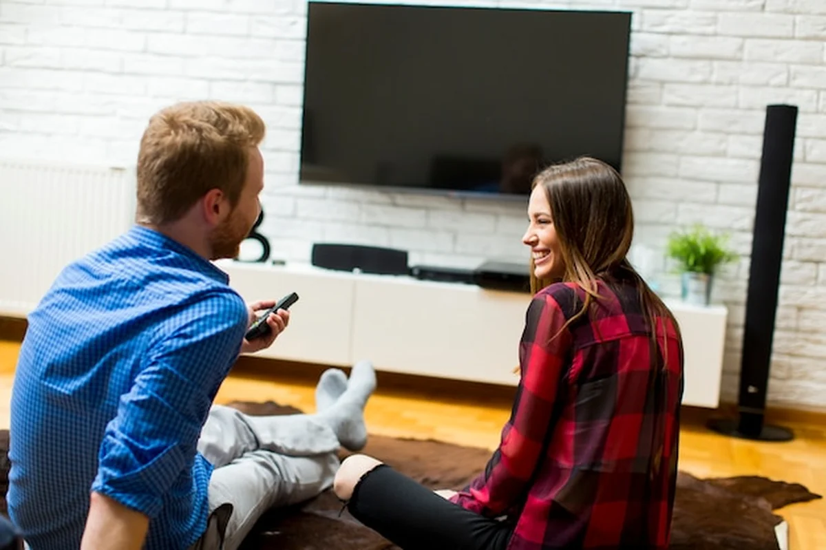 Para oglądająca telewizję siedząca na podłodze