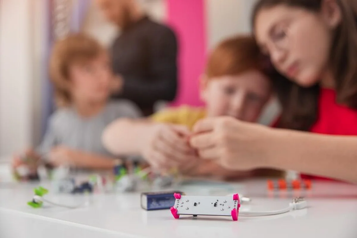 Grupa uczniów szkół podstawowych ucząca się robotyki z nauczycielem w nowoczesnej klasie