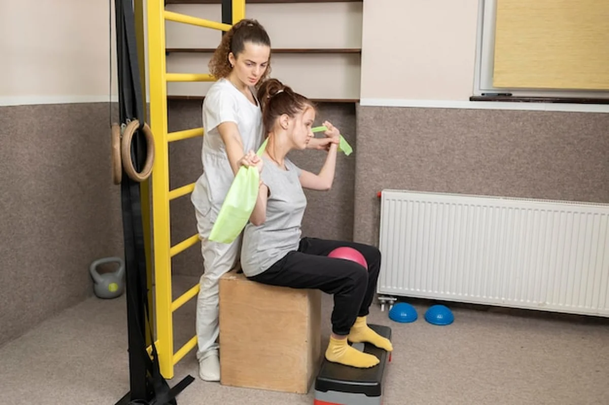 Dziecko niepełnosprawne i lekarz ćwiczą w sali rehabilitacyjnej