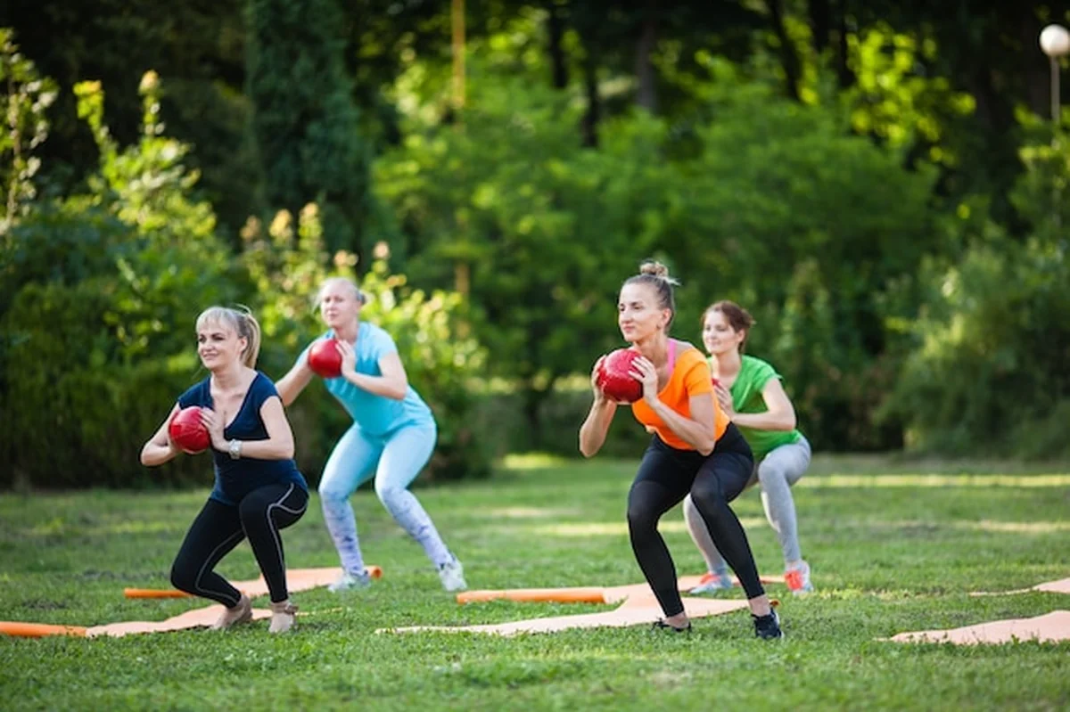Grupa dziewcząt ćwiczy z piłkami fitness w parku