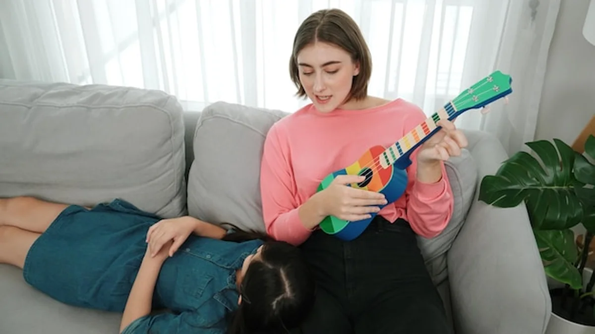 Dziewczynka słuchająca muzyki akustycznej na kolanach matki na kanapie