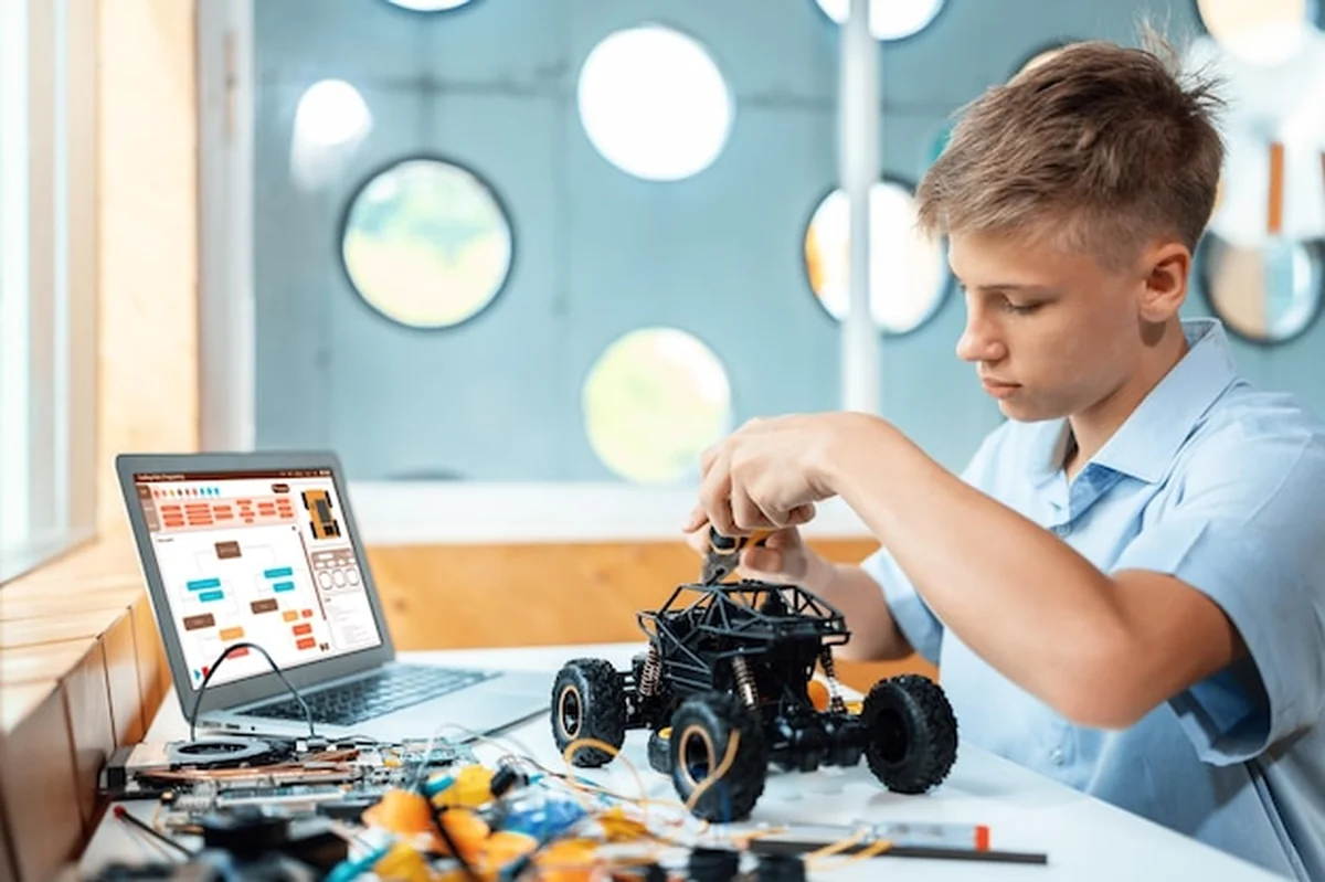 Uczeń naprawia samochód robotyczny w klasie STEM Budownictwo