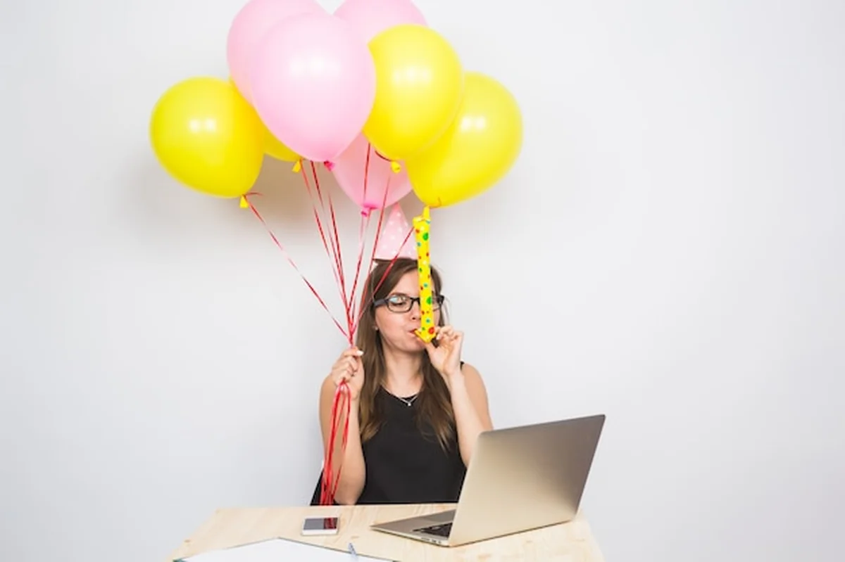 Młoda kobieta trzyma kolorowe balony w biurze