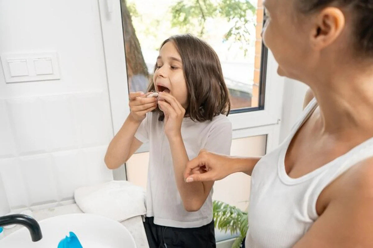 Matka pomaga dziecku założyć protezę do zębów