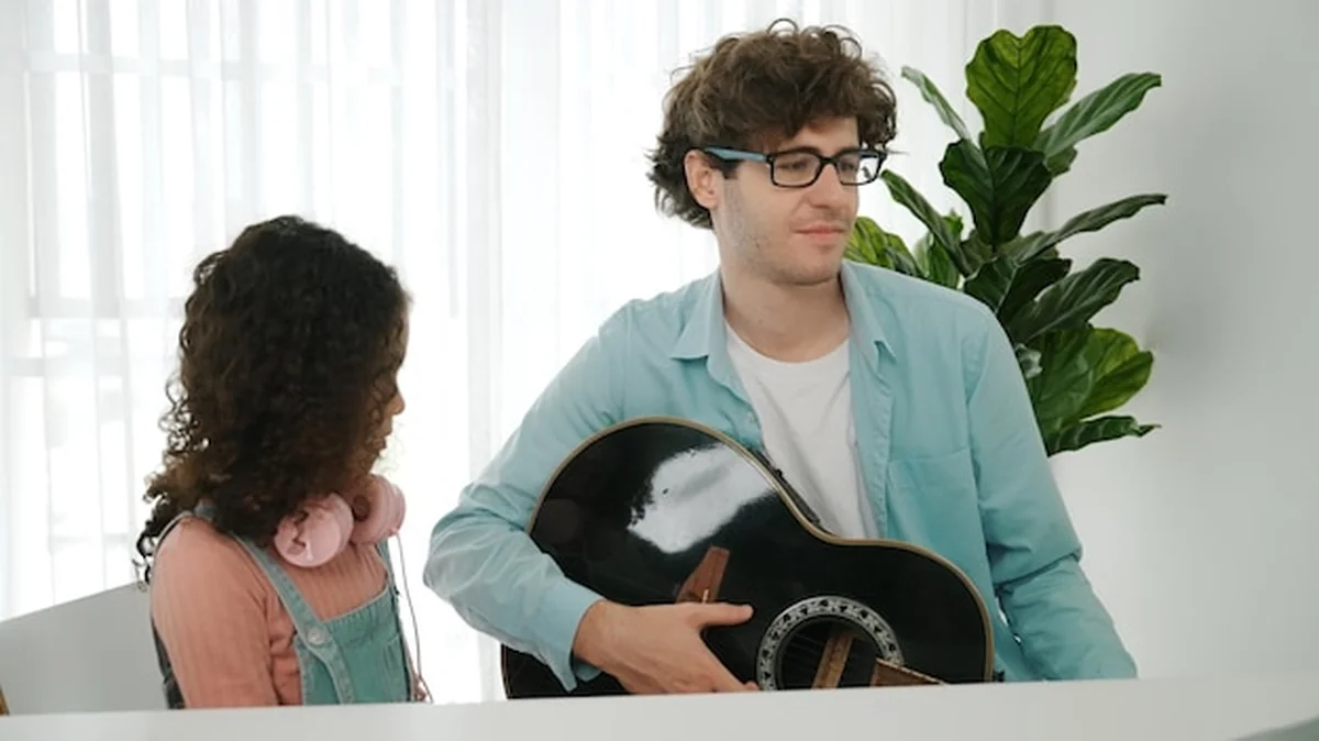 Ojciec gra na gitarze dla zrelaksowania córki po nauce kodowania Pedagogii